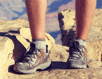 A hiker stands on a mountaintop with two layer socks and boots
