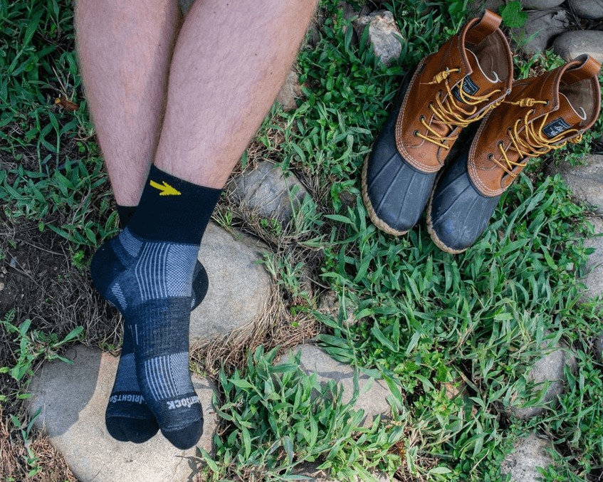 Man resting in quarter socks beside hiking boots