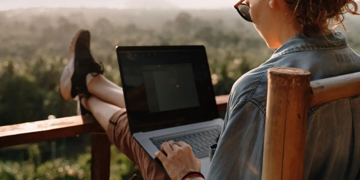 A woman working on a laptop overlooking a valley.