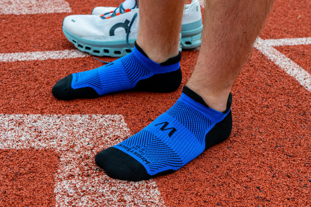 A person standing on a track in Wrightsock Royal Blue Racer Tab socks.